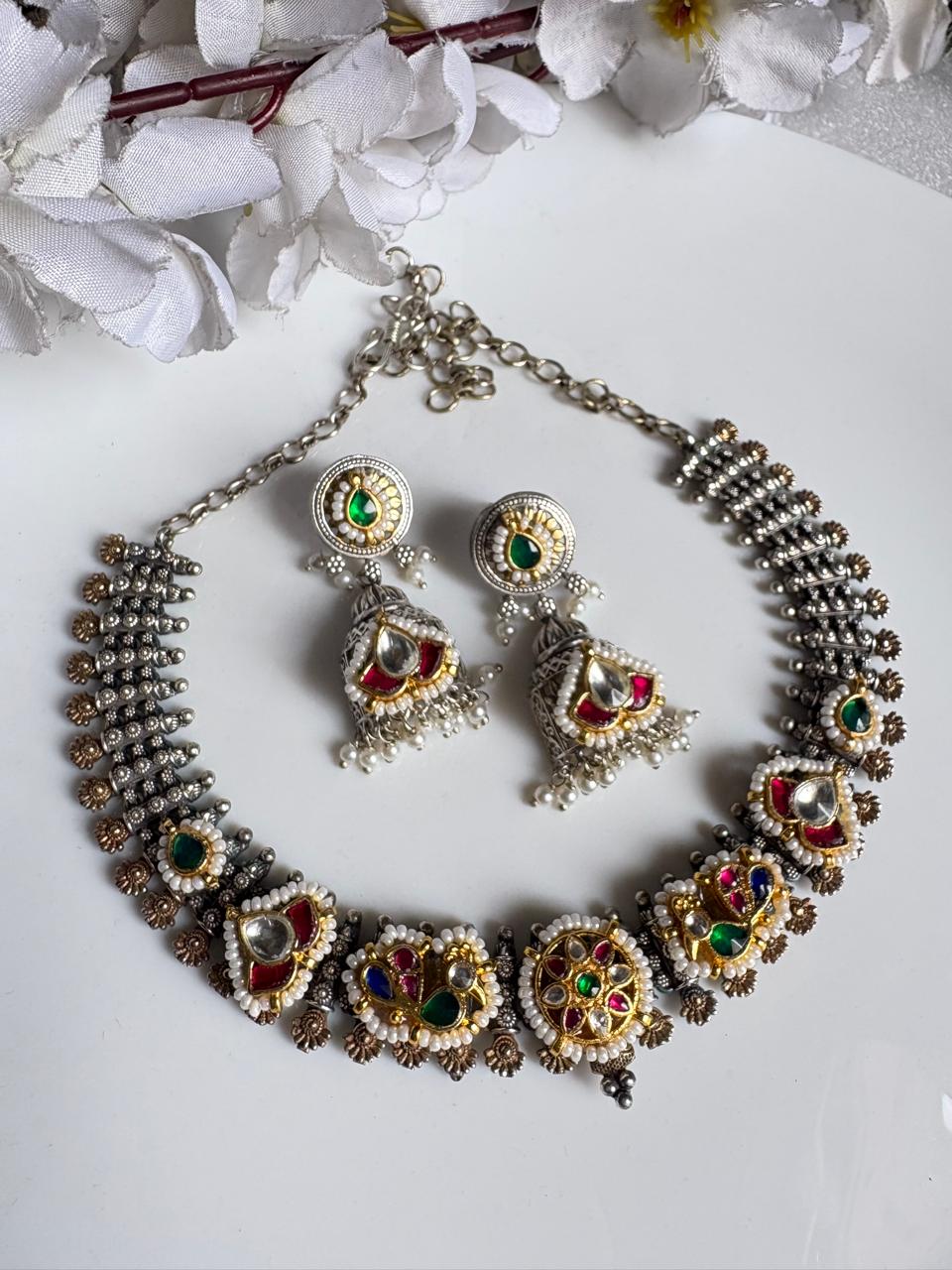 Ornate necklace and earrings set with gemstones on a white background