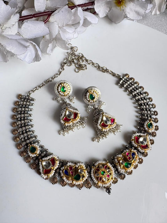 Ornate necklace and earrings set with gemstones on a white background