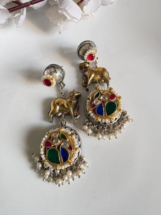 Ornate earrings with colorful gemstones and animal figures on a white background